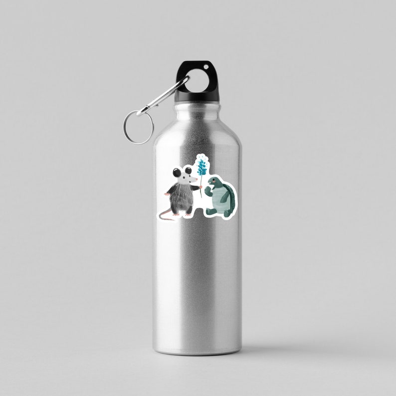 May include: A silver water bottle with a black lid and a sticker of a possum giving a flower to a turtle.
