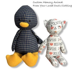 May include: Two handmade stuffed animals: a penguin and a cat. The penguin is navy blue with a plaid pattern, yellow beak and feet. The cat is white with a repeating "Elvis I Love" print and red hearts. Text above reads "Custom Memory Animal From Your Loved One's Clothing."