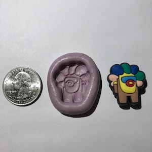 May include: A purple silicone mold for making a small, yellow character with a blue, green, and yellow hat. The character is similar to the popular video game Among Us. The mold is next to a quarter for size reference.
