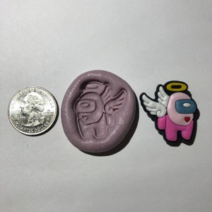 May include: A pink and white angel-themed Among Us character with wings and a halo. The character is made of silicone and is about the size of a US quarter. There is also a silicone mold of the character.