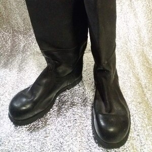 May include: A pair of black leather knee-high boots with a rounded toe and a thick sole.