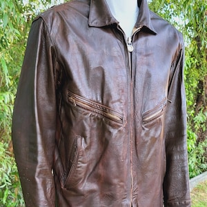 May include: A brown leather jacket with a zip fastening and multiple pockets. The jacket has a worn look and a classic style.