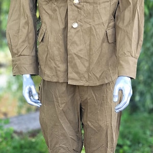 May include: A vintage military uniform in a khaki green colour. The jacket has a button-up front and a collar. The trousers have a straight leg and are made of a durable fabric.