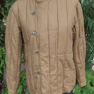 May include: A brown quilted jacket with a stand-up collar and four buttons down the front. The jacket has a patch pocket on the right side and a seam down the centre of the back.