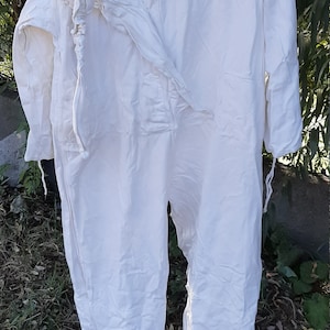 Op de afbeelding: Een witte hooded jumpsuit met een trekkoord in de taille en aan de polsen. De jumpsuit is gemaakt van een lichtgewicht stof en heeft een ontspannen pasvorm.