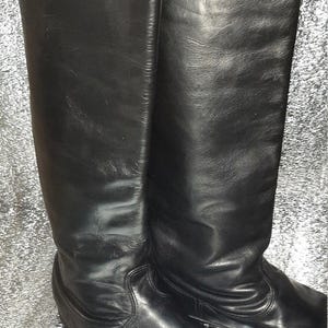 May include: A pair of black leather knee-high boots with a pointed toe.