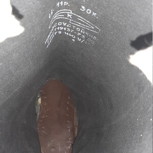 May include: Close-up of the inside of a black leather boot with white markings. The markings include the numbers 29, 43, 277, and 30K, as well as the letters "11P" and "R".