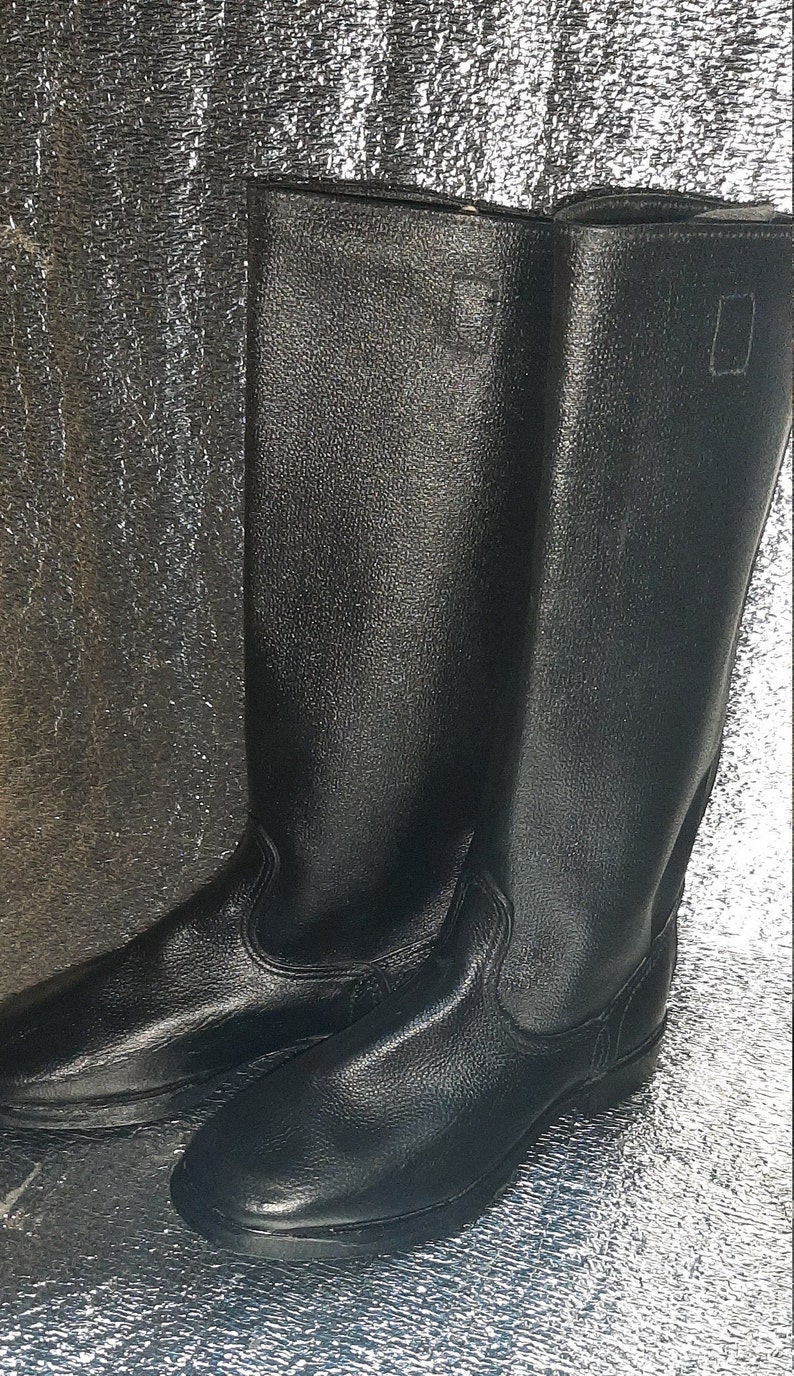 May include: A pair of black leather boots with a tall shaft and a rounded toe. The boots have a simple design and are made of a durable material.