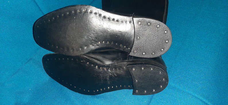 May include: A pair of black leather boots with a stitched sole and a row of metal studs around the edge.