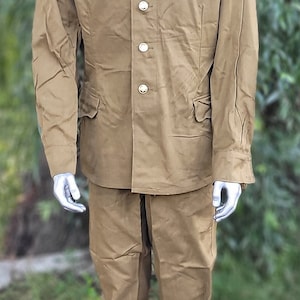 May include: A khaki military uniform with a button-up jacket and matching trousers. The jacket has a stand-up collar and five buttons down the front.