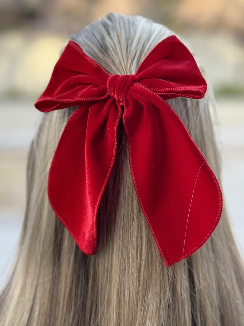 Puede incluir: Un gran lazo de terciopelo rojo para el cabello. El lazo est&aacute; atado en un estilo cl&aacute;sico y de gran tama&ntilde;o con colas largas.
