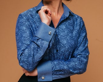 May include: A blue paisley patterned long-sleeve shirt with a white collar and cuffs. The shirt has a button-up closure and features silver cufflinks.