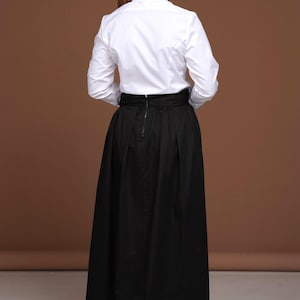 Back view of the white striped blouse from DaDonna Blouses, showcasing the impeccable fit and fabric quality. The shirt’s tailoring is crisp and feminine, crafted from premium 100% cotton. Styled with a dramatic black high-waisted skirt, this top is perfect for women who value refined elegance in their wardrobe. SEO-focused keywords: white cotton blouse, womens tops dressy, high collar blouse.