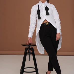 Full-length editorial styling of tuxedo shirt women with long back tailcoat effect; business blouse and evening statement top in one piece.