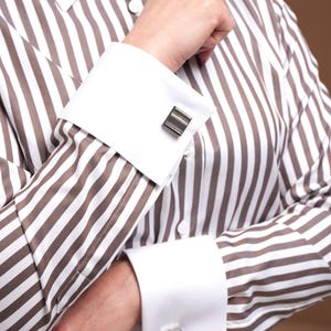 Close-up portrait showcasing the rich texture of the striped French cuff shirt with cufflinks. Made in limited editions at a specialized European factory, this premium women’s shirt features double cuffs, a white pointed collar, and exceptional stitching. Ideal for women who seek powerful professional style with uncompromising quality. A wardrobe essential with lasting value.