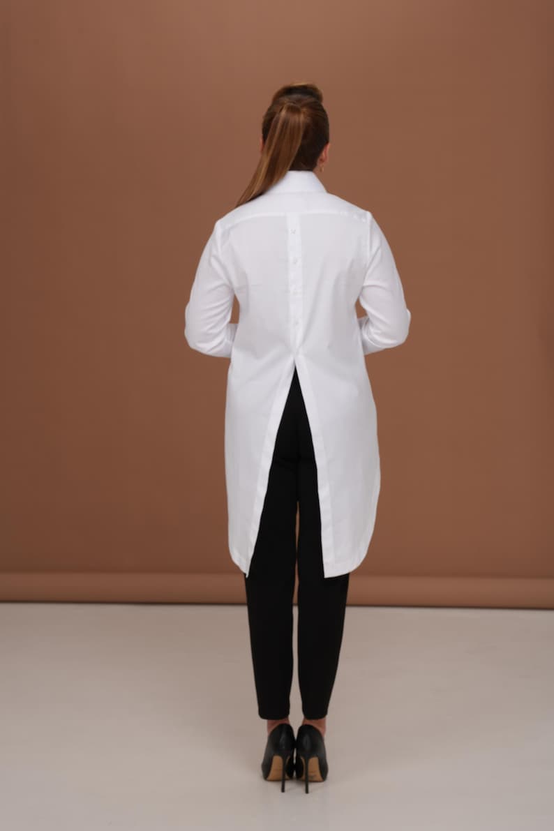 Back view of white shirt women with long tailcoat back and center back placket detail; crisp silhouette, high collar shirt shape, elegant womens dress shirt proportions.