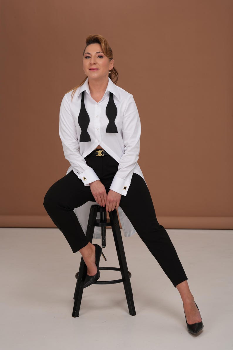 White tuxedo shirt for women in full-length styling, high collar statement dress shirt with tailcoat-style long back; French cuffs designed as a cufflink shirt (cufflinks not included).
