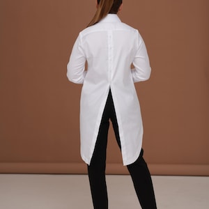 Back silhouette photo emphasizing long back blouse shape and tailcoat-style hem; white womens dress shirt designed for sharp, elegant wear