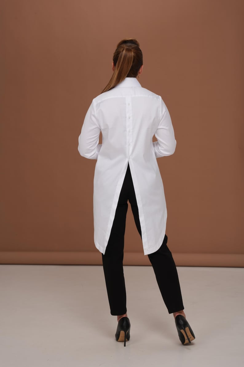 Back silhouette photo emphasizing long back blouse shape and tailcoat-style hem; white womens dress shirt designed for sharp, elegant wear