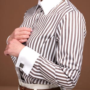 Macro shot of the French cuff and cufflink detail on a luxury women’s striped dress shirt. Featuring a white double cuff and premium cotton fabric, this button down shirt offers durability, elegance, and sharp style. Designed in Europe, it’s a timeless wardrobe essential for women who demand the highest quality and fashion-forward functionality in professional attire.