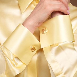 Close-up portrait showing the French cuffs with subtle gold cufflinks and the silky smooth texture of the blouse. The fine weave of the silk, soft sheen, and precision stitching reflect the craftsmanship behind this premium-quality French cuff blouse for women