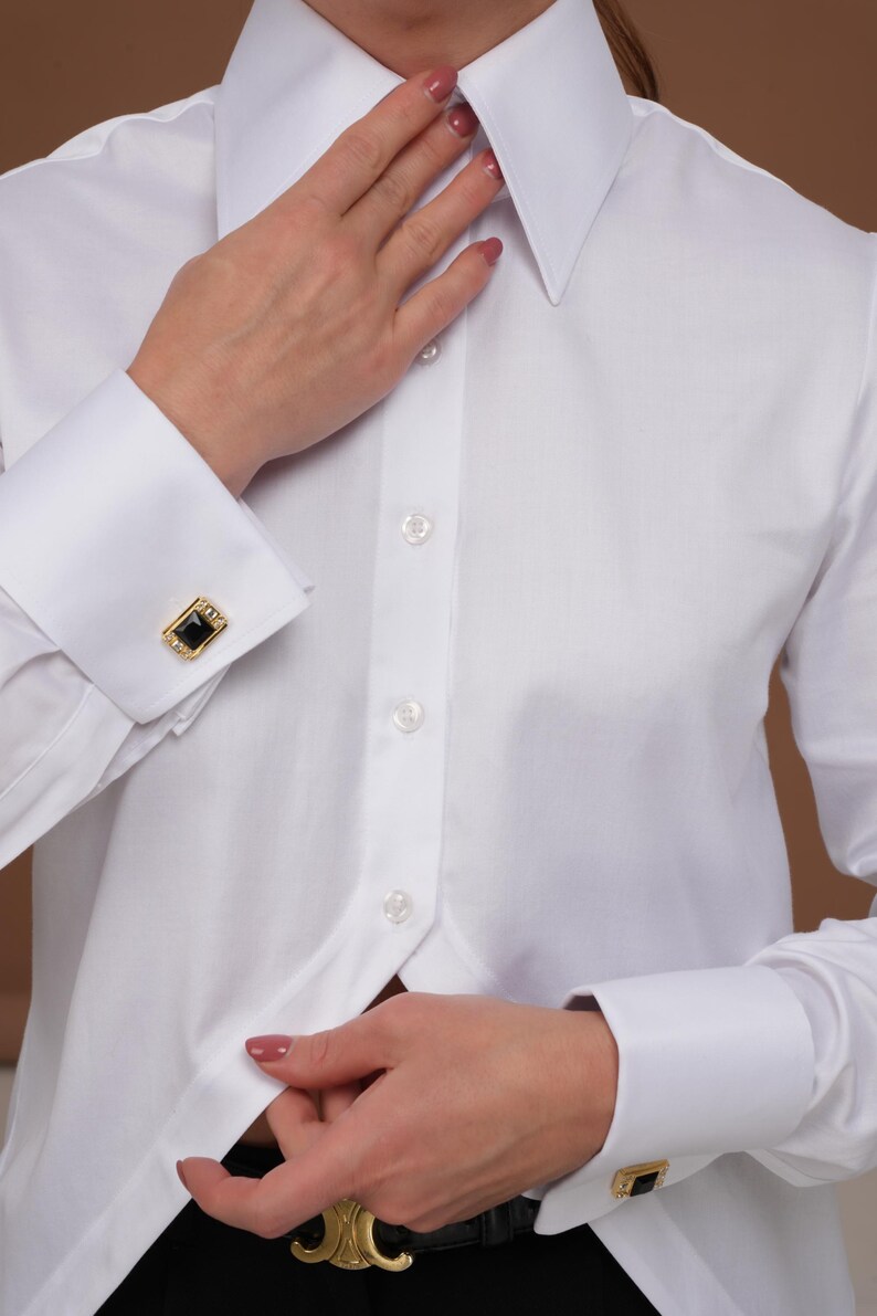 Three-quarter portrait in a white tuxedo blouse, statement collar and clean lines; French cuffs visible as a cufflink shirt women can style for evenings (cufflinks not included).