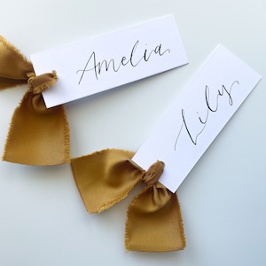 Cartão de nome de lugar com caligrafia e fita de cetim DOURADO | Cartão de nome de lugar branco personalizado | Ilhós dourados | Conjunto de mesas para casamento | Plano de assentos