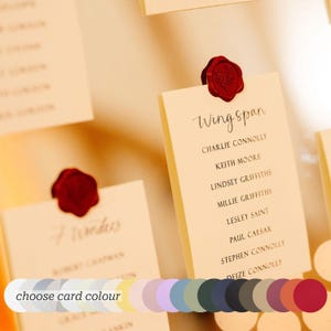 May include: Cream-coloured rectangular table cards featuring black printed text and a red wax seal at the top. The cards display names under headings like Wingspan and 7 Wonders. A colour palette bar is visible at the bottom with the text choose card colour.