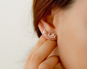 May include: Gold-toned nameplate earrings with the name "Michelle" spelled out in a cursive font.