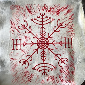 May include: A white, textured surface with a central red symbol resembling a snowflake or compass rose. The symbol is surrounded by radiating lines and smaller, stylized elements. The design is reminiscent of ancient Nordic art.