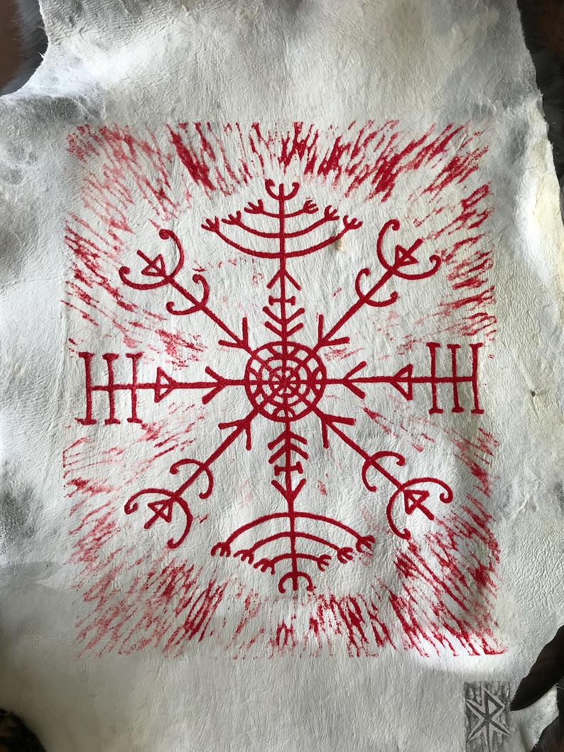 May include: A white, textured surface with a central red symbol resembling a snowflake or compass rose. The symbol is surrounded by radiating lines and smaller, stylized elements. The design is reminiscent of ancient Nordic art.