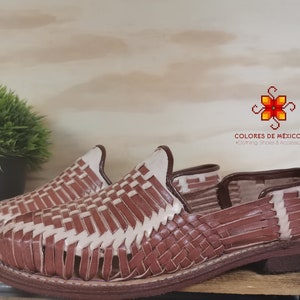 K&ouml;nnte beinhalten: Ein Paar braune Ledersandalen mit gewebtem Muster. Die Sandalen haben einen wei&szlig;en Lederbesatz und eine braune Ledersohle.