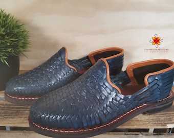 May include: A pair of blue leather sandals with a woven pattern and brown leather trim. The sandals have a closed toe and a low heel.
