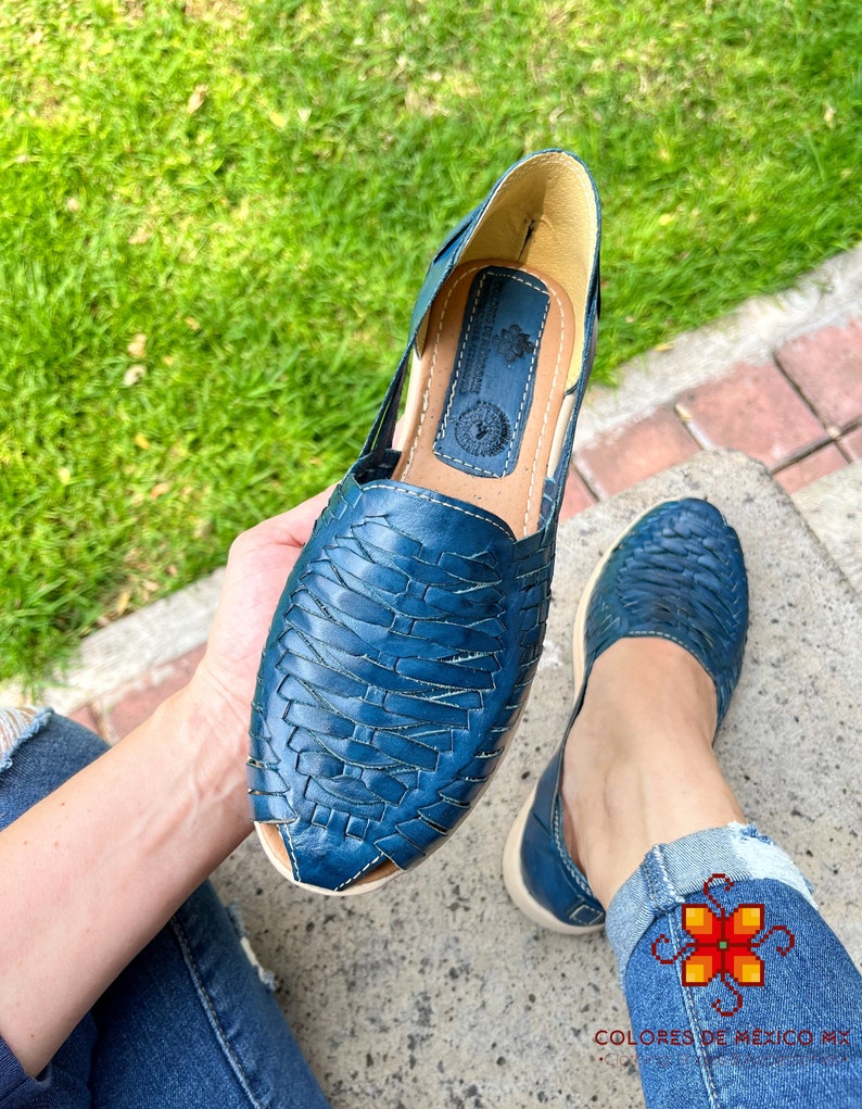 May include: A pair of blue leather sandals with a woven design. The sandals have a pointed toe and a flat sole.