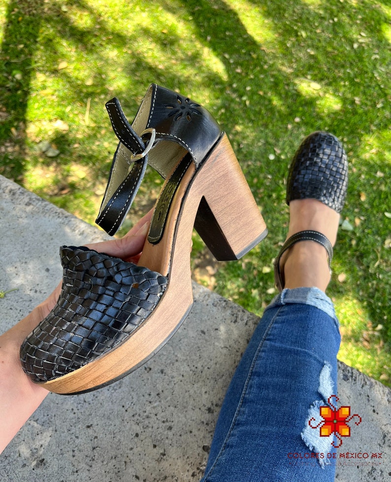 Op de afbeelding: Zwarte geweven platform sandalen van leer met een houten hak. De sandalen hebben een band met een gespsluiting.