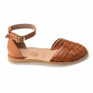 May include: Tan leather sandals with an ankle strap and woven leather upper. The sandals have a flat sole and a simple design.