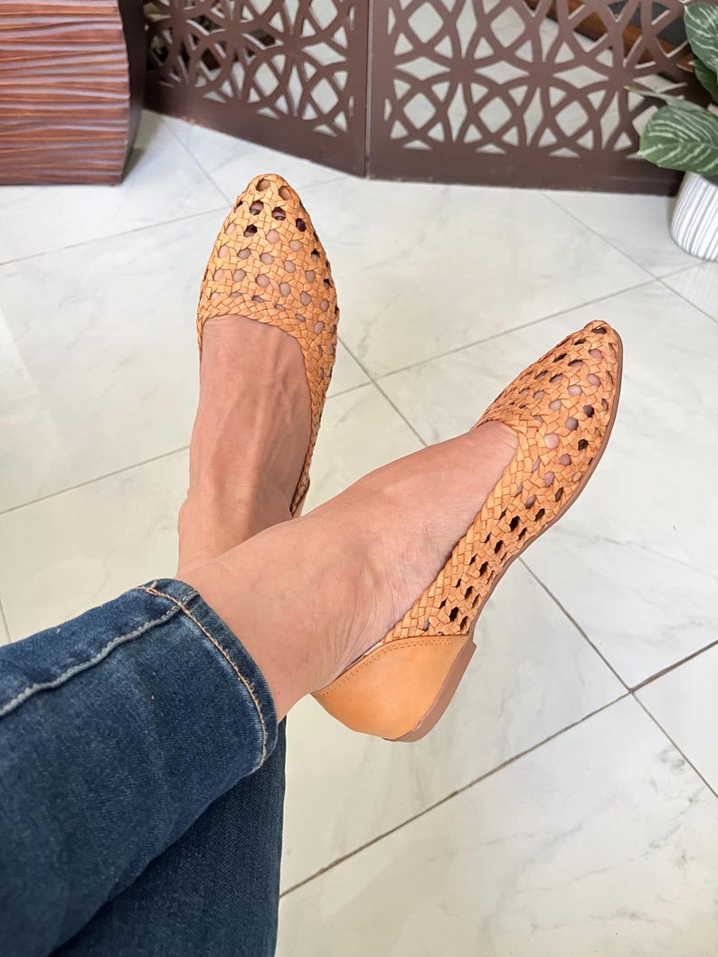 K&ouml;nnte beinhalten: Ein Paar beigefarbene geflochtene Lederschuhe mit spitzer Zehenpartie. Die Schuhe haben ein geflochtenes Muster mit kleinen L&ouml;chern.