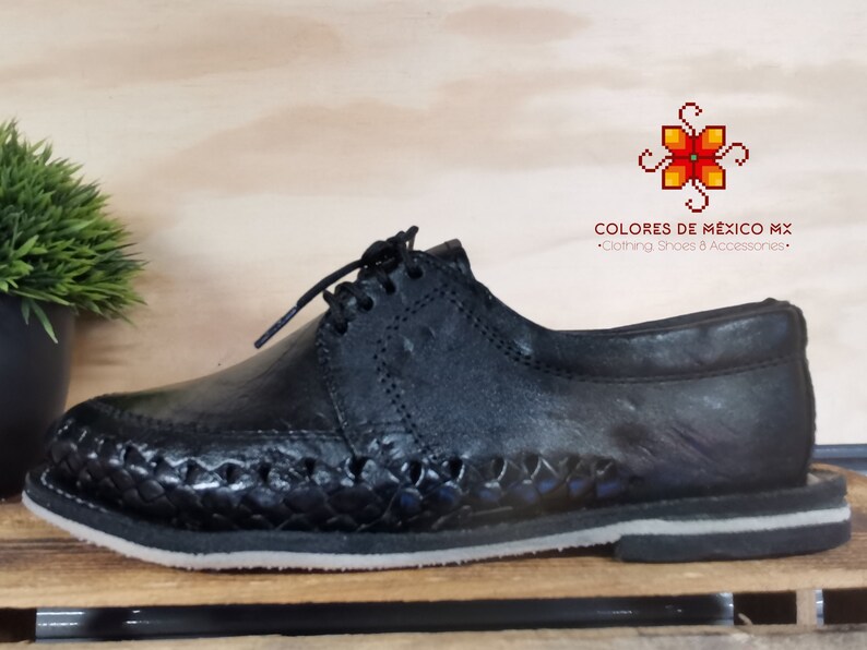 May include: Black leather shoes with a woven design on the sole. The shoes have a lace-up closure and a rounded toe. The brand name "COLORES DE M&Eacute;XICO MX" is printed on the shoe.