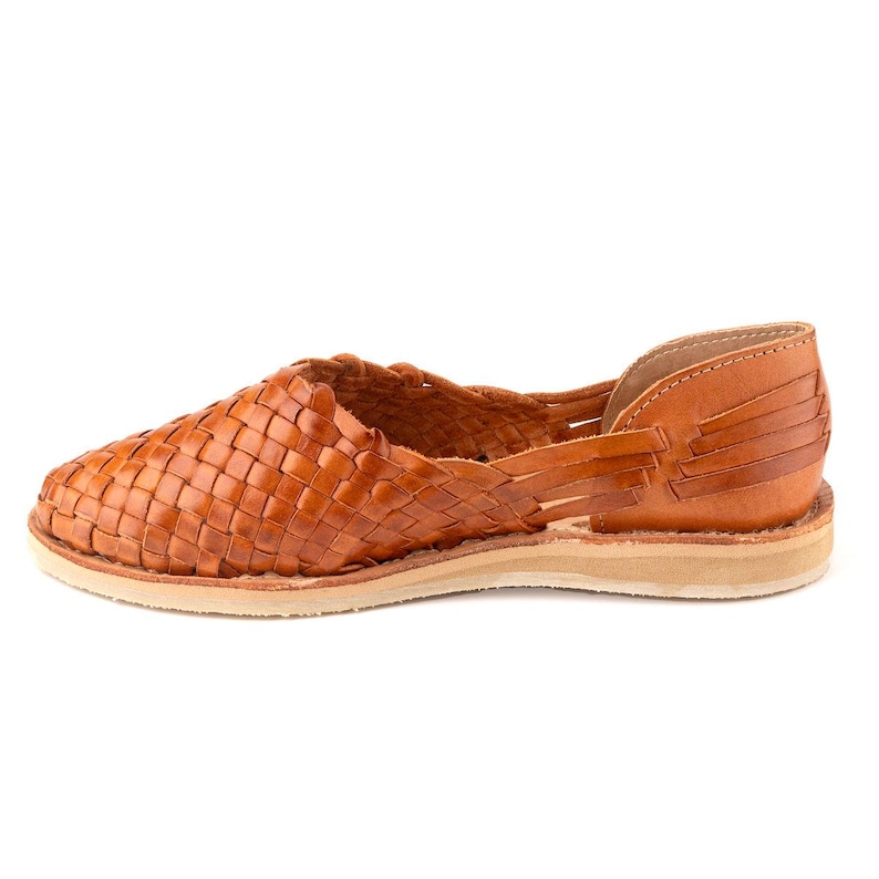 Pu&ograve; includere: Un paio di sandali in pelle marrone con un design intrecciato. I sandali hanno una suola piatta e una punta aperta.