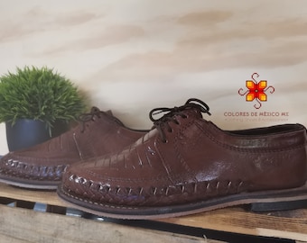 May include: A pair of brown leather shoes with a woven design on the sole. The shoes have a lace-up closure and a slightly pointed toe. The brand name "COLORES DE MÉXICO MX" is visible on the right shoe.