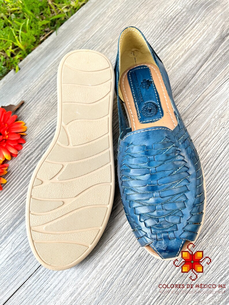 May include: A pair of blue leather sandals with a woven design. The sandals have a beige sole with a textured pattern.