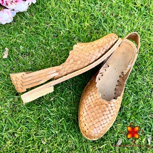 Puede incluir: Un par de sandalias de cuero trenzado de color marr&oacute;n claro. Las sandalias tienen un dise&ntilde;o sencillo con una tira trenzada sobre la parte superior del pie y una tira alrededor del tobillo.