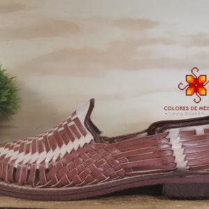 K&ouml;nnte beinhalten: Braune Ledersandalen mit gewebtem Design. Die Sandalen haben einen wei&szlig;en Lederbesatz und eine braune Ledersohle.
