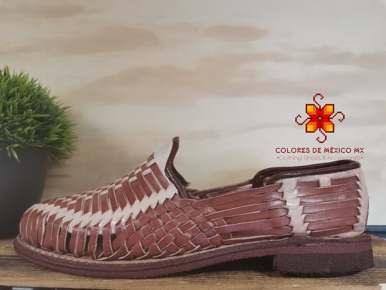 K&ouml;nnte beinhalten: Braune Ledersandalen mit gewebtem Design. Die Sandalen haben einen wei&szlig;en Lederbesatz und eine braune Ledersohle.