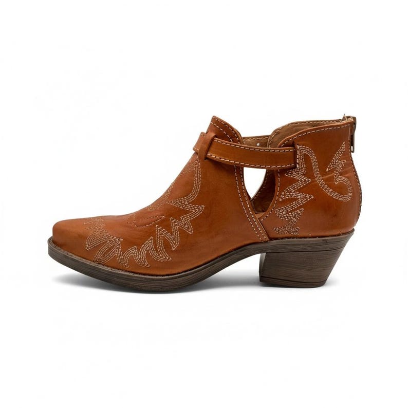 Pu&ograve; includere: Stivaletto in pelle marrone con punta e tacco piccolo. Lo stivale presenta cuciture decorative e chiusura con fibbia. Il lato dello stivale ha un design ritagliato. Stivale in stile western.