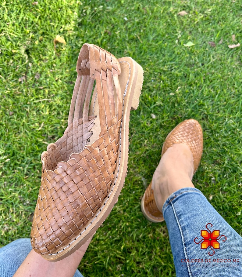 Puede incluir: Sandalias de cuero color marr&oacute;n claro con dise&ntilde;o tejido. Las sandalias tienen la punta cerrada y el tal&oacute;n abierto. Las sandalias las lleva puestas una persona con pantalones vaqueros azules.