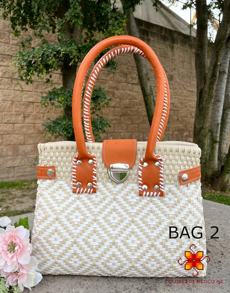 May include: A white and tan woven tote bag with a brown leather handle and a silver clasp. The bag has a diamond pattern and the text "BAG 2" is visible in the lower right corner.