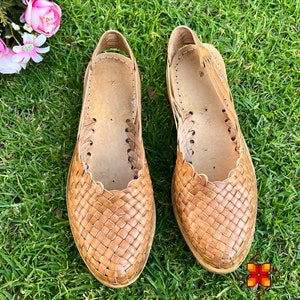 Puede incluir: Un par de sandalias de cuero trenzado de color marr&oacute;n claro. Las sandalias tienen un dise&ntilde;o sencillo con una correa que va alrededor del tobillo.