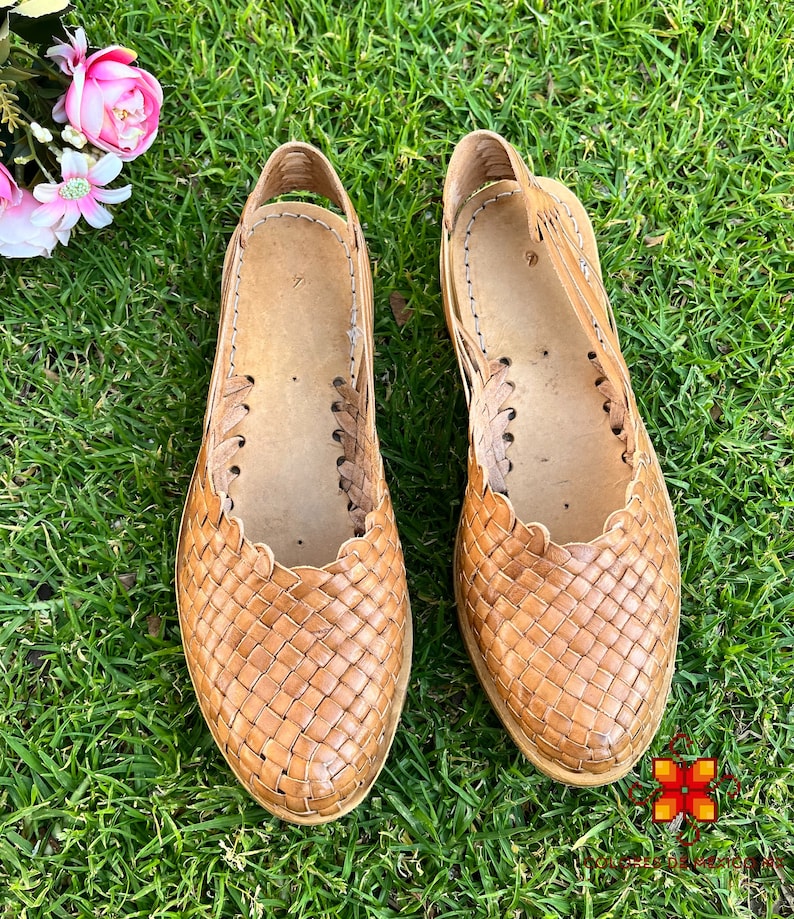 Puede incluir: Un par de sandalias de cuero trenzado de color marr&oacute;n claro. Las sandalias tienen un dise&ntilde;o sencillo con una correa que va alrededor del tobillo.