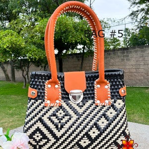 May include: A black and white woven tote bag with orange leather handles and a silver clasp. The bag has a geometric pattern and the text "BAG #5" is visible in the image.
